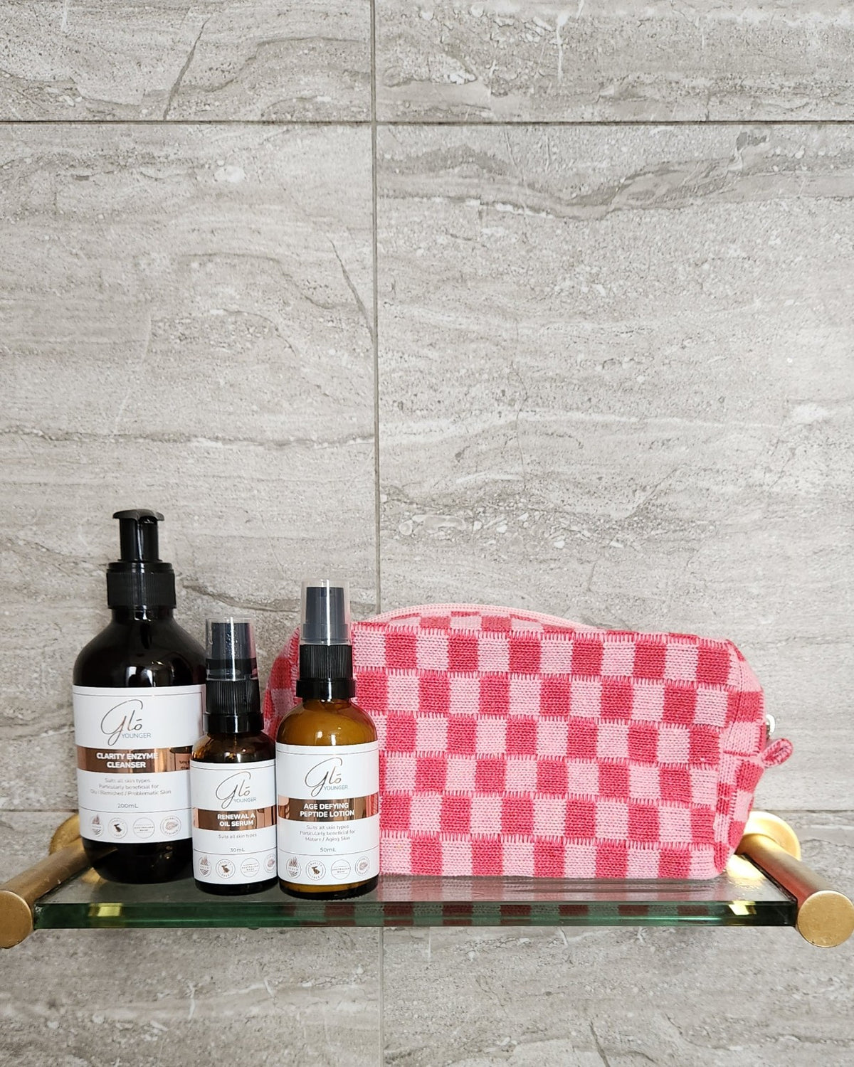 Pink checkerboard cosmetic bag with Glo Younger cleanser, renewal oil serum and peptide lotion